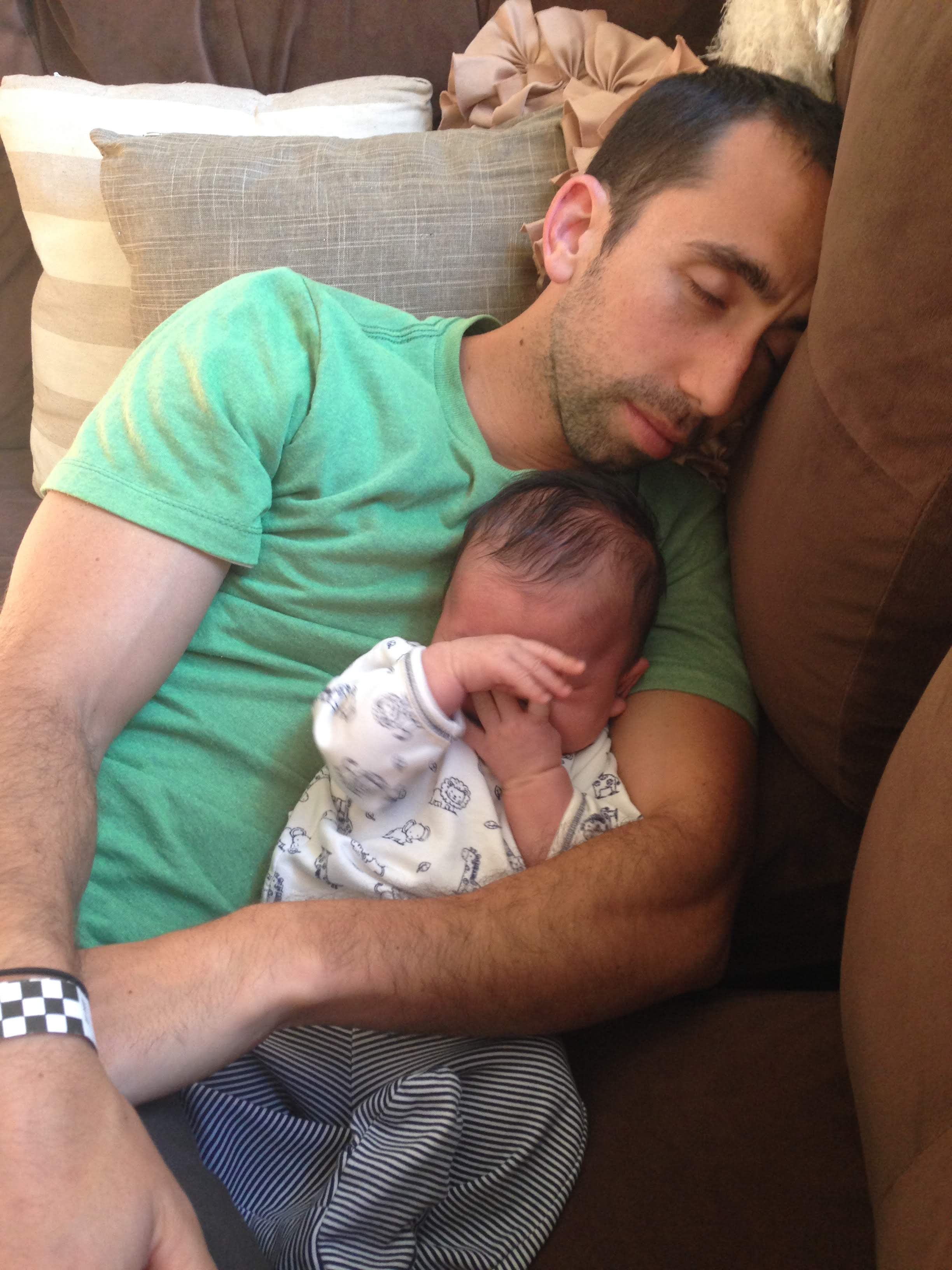 Parent sleeping while holding baby in arms