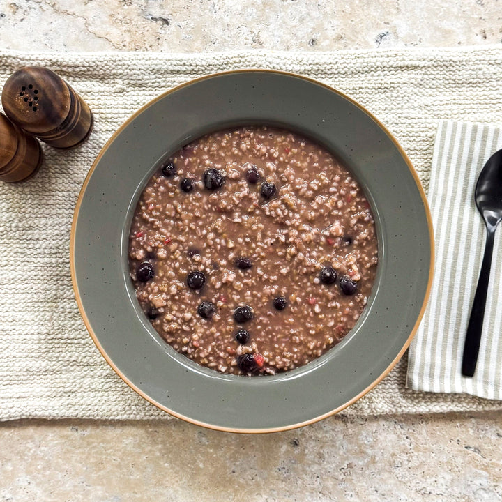 Very Berry Oatmeal Congee with blueberries in a large gray bowl
