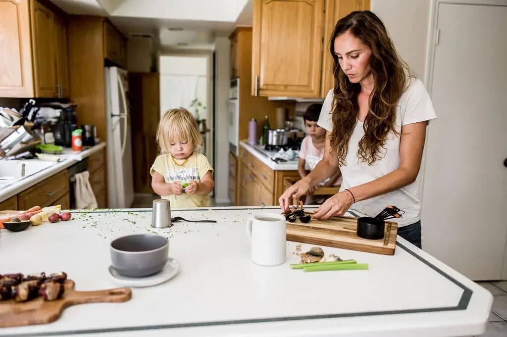 Woman and two young children preparing food in a kitchen.