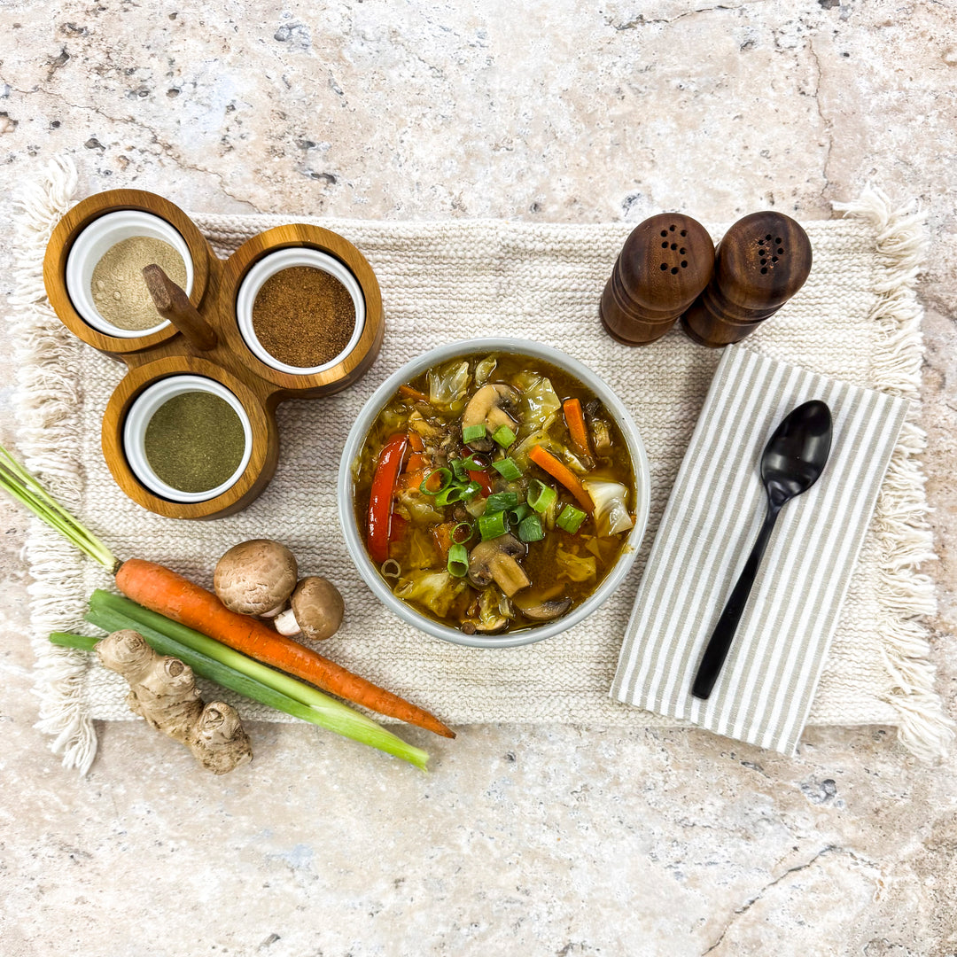 Mongolian Beef bowl surrounded by fresh carrots, mushrooms, ginger, green onions, and spices